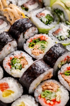 Oriental traditional seafood. Close up of original sushi rolls with different fillings standing and lying close to each other. Macro view of sushi set with different ingredients inside.