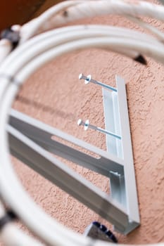 Unscrewed screws on metal holder of wall air conditioner. Close up of mounting parts for outdoor air conditioner unit. Concept of installing air conditioning system.