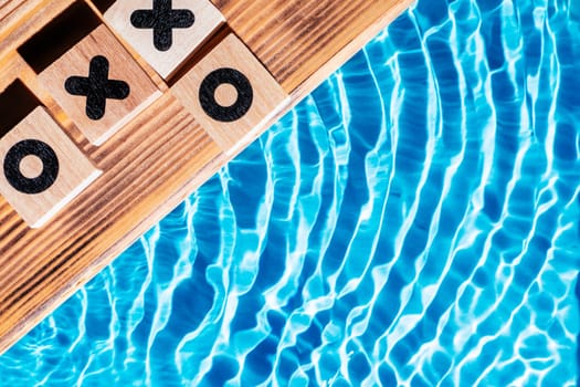 Wood sand board coastal with timbered dibs. Blue tide flowing transparent reflect wave water surface ocean. Rivalry playing, cubes noughts, crosses, tick tack toe game. Flat lay. Right place for text.