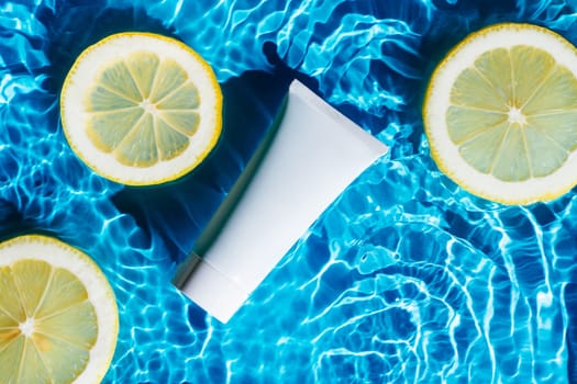 White beauty product sunscreen cream vial tube bottle in transparent fresh water with flecks with lemon citrus. Body skin care in summer beach travel concept. Protection UV rays, sunbathing. Flat lay.