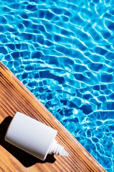 Wood desk with white bottle of nose drops, allergy aerosol for sinusitis cure. Control breath. Blue transparent reflect water surface ocean. Hot warm dry air summer beach. Vertical. Place for text.