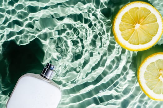 White square perfume bottle on green blue transparent reflect rippled wave water surface, lemon citrus slices. Fashion dermatology skin care. Right copy space. Place for text. Top view