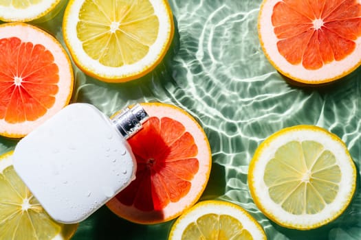 White square perfume bottle on green blue transparent reflect rippled wave water surface, lemon and grapefruit citrus slices. Fashion dermatology skin care. Right copy space. Place for text. Top view