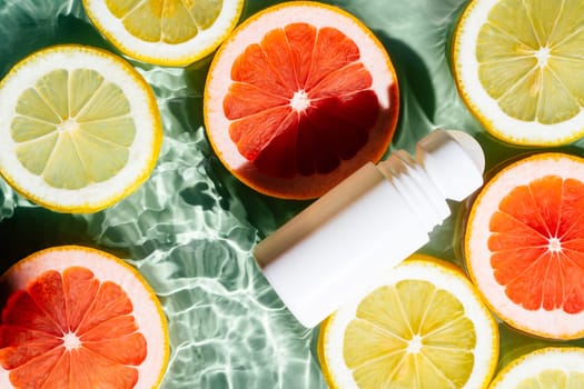 White beauty product roll on antiperspirant deodorant anti sweat smell, vial on green blue transparent reflect rippled wave water surface, lemon and grapefruit citrus slices. Skin protection. Top view