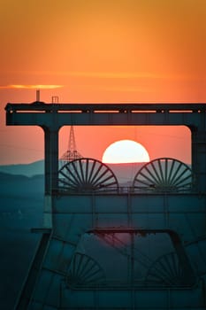 Vertical shot of a headframe tower with a golden sun setting in the background in Herten, Germany