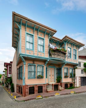 Exterior facade of old colorful wooden residential building with door, wrought iron windows, balcony, and green climber plants, Fatih district, Istanbul, Turkey