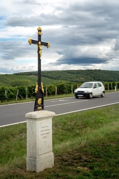 religious cross near a road with car