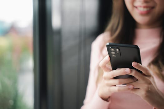 Happy beautiful female typing text message on smart phone device and enjoyment lifestyle with social networking media, Asian young woman using mobile phone at cafe coffee shop to shopping online
