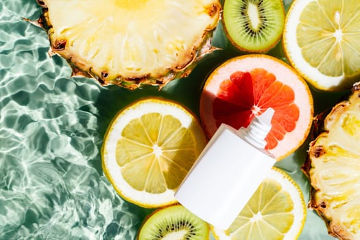 White beauty product sunscreen cream vial tube bottle with fruit citrus lemon, kiwi, orange, pineapple, grapefruit, lemon water splash transparent surface, flecks. Body skin care in summer. Flat lay.