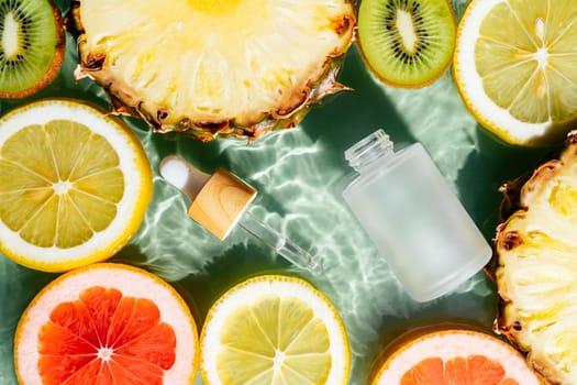 Facial pipette serum, whey beauty product near fruit citrus lemon, kiwi, orange, pineapple, grapefruit in water fresh transparent. Flat lay, top view. Organic skin body care in hot climate