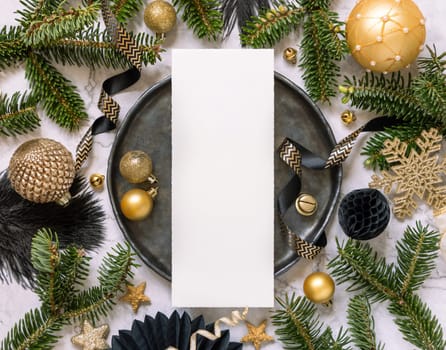 Black and golden Table setting with ornaments and fir tree branches, card mockup. Christmas or New Year menu on marble table flat lay, copy space. Winter season, restaurant holiday catering