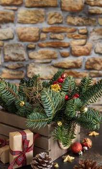 Wrapped gift boxes near Christmas decorations, pine cones and green fir branches close up with copy space, close up with brick wall. Christmas or New Year Holiday atmosphere composition