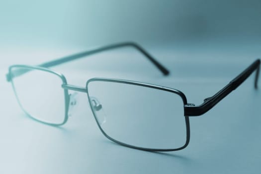 Glasses in a black frame on a blue background with copy space. World Day of Sight. Blurred background