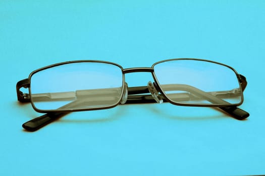 Glasses in a black frame on a blue background with copy space. World Day of Sight.