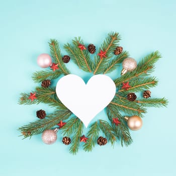 Christmas holiday background in heart shape, frame with fir branches, baubles and pine cones, winter season greeting card