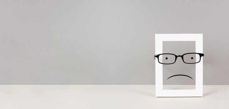Frame with a sad face, mental health concept, negative mindset, depression, support and evaluation symbol