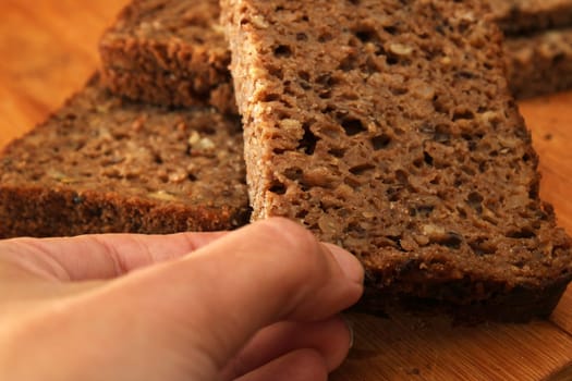 Woman's hand taking whole grain bread, close-up. Healthy food concept. Defocus.