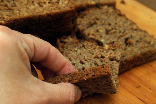 A woman breaks off a piece of whole grain bread. Defocus. Healthy food concept.