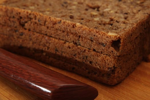 Sliced whole grain bread with a knife close-up on a wooden board. Defocus. Healthy food concept.
