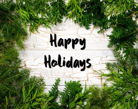 Christmas Card With Fir Branches And English Text Happy Holidays. White Wooden Background With Vintage Design.