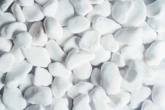Creative background abstract image of medium-sized white rounded smooth pebble stones. Backdrop stone pattern surface. Copy space. Top view, flat lay