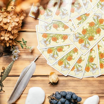 Tarot cards fanned face down on wooden surface with stones, autumn plants and accessories. Top view. Minsk, Belarus, 11.10.2021