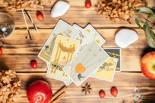 Tarot cards spread face up on wooden surface with stones, autumn plants and accessories. Top view. Minsk, Belarus, 11.10.2021