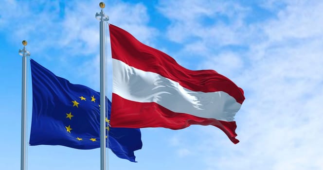 Detail of the national flag of Austria waving in the wind with blurred european union flag in the background on a clear day. Democracy and politics. European country. Selective focus.