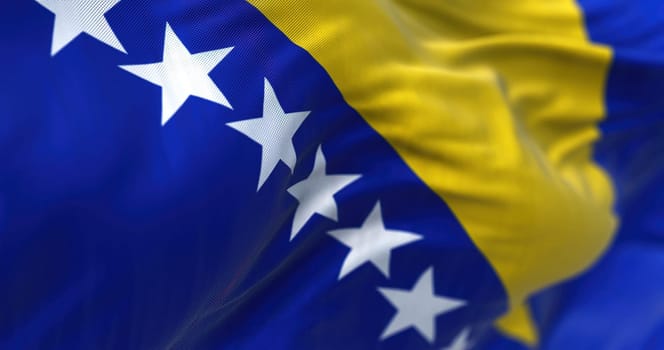 Close-up view of the bosnian national flag waving in the wind. Bosnia and Herzegovina is a country at the crossroads of south and southeast Europe. Fabric textured background. Selective focus