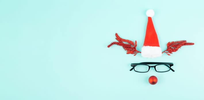 Reindeer with a red bauble nose, antlers, a santa claus hat and eyeglasses, merry christmas greeting card