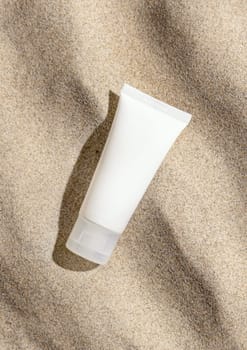 White cream tube on beige sand top view, hard light. Package mockup. Natural skincare or SPA product. Facial cosmetics for beauty routine. Zen style with waves on sand, minimal aesthetic