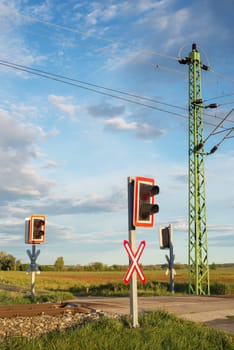 A closing barrier and red traffic light at the railway crossing. railway station.