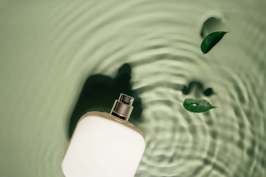 White square perfume bottle on green transparent reflect rippled wave water surface, small leaves of Ficus Benjamin. Fashion dermatology skin care. Copy space. Place for text. Top view
