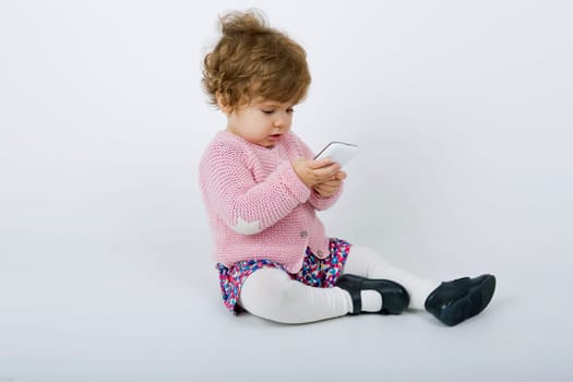 young baby with a phone on a grey background