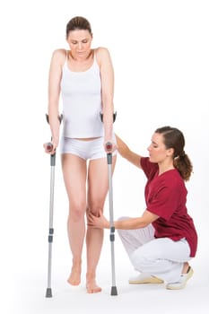 woman with crutch at the physiotherapist doing legs rehabilitation.