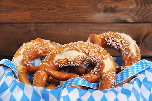 Three original Bavarian lye pretzels with salt in front of a wooden wall
