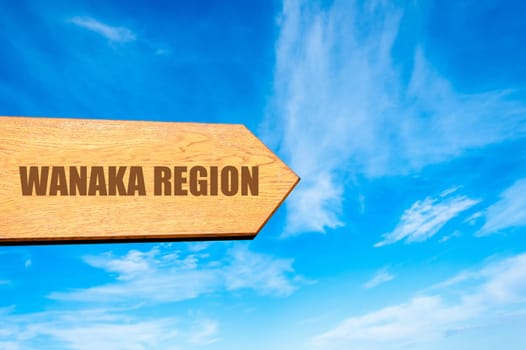 Wooden arrow sign pointing destination WANAKA REGION, NEW ZEALAND against clear blue sky with copy space available. Travel destination concept  image
