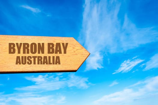 Wooden arrow sign pointing destination BYRON BAY, AUSTRALIA  against clear blue sky with copy space available. Travel destination concept  image