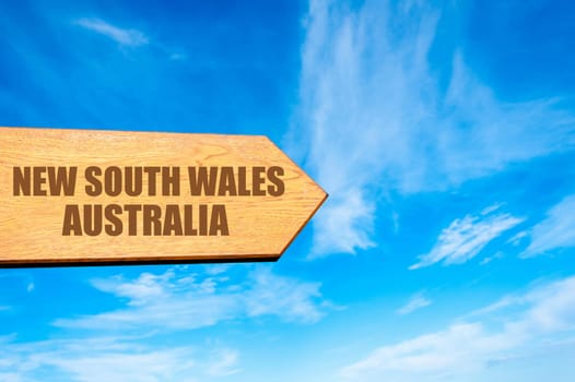 Wooden arrow sign pointing destination NEW SOUTH WALES, AUSTRALIA  against clear blue sky with copy space available. Travel destination concept  image