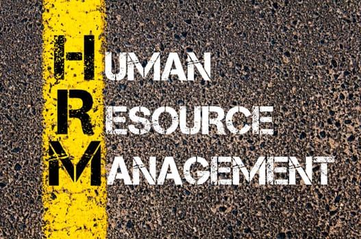 Concept image of Business Acronym HRM as HUMAN RESOURCE MANAGEMENT written over road marking yellow paint line.