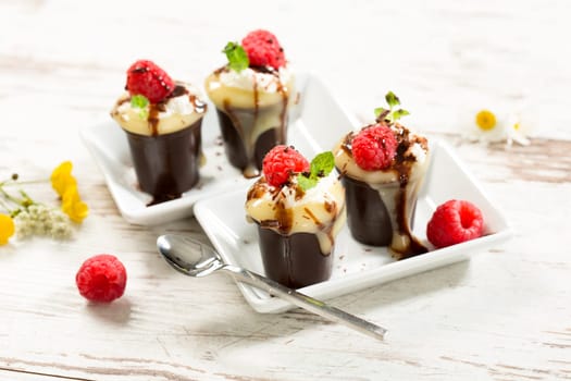 Chocolate cups with vanilla pudding,cream and raspberries
