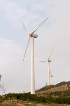 White electrical power generating wind turbines on rolling hills
