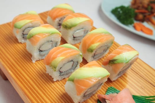 sushi with salmon and avocado on wooden plate