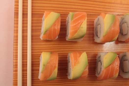 sushi with salmon and avocado on wooden plate