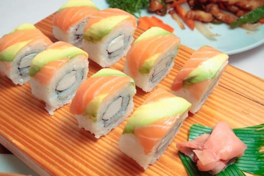 sushi with salmon and avocado on wooden plate