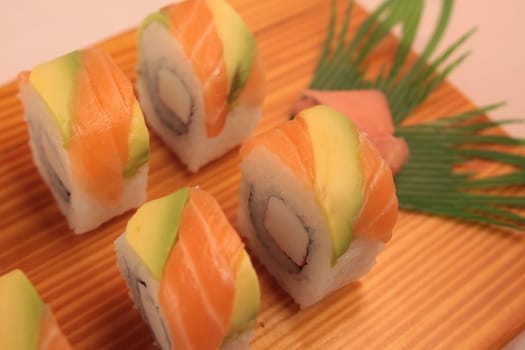 sushi with salmon and avocado on wooden plate
