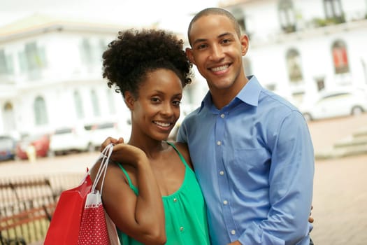 Portrait of black tourist heterosexual couple in Casco Antiguo - Panama City with shopping bags. The man and his girlfriend smile at the camera