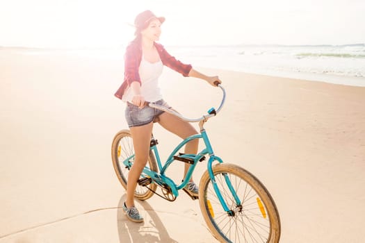 An attractive young woman riding her bicycle on the beach