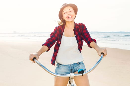 An attractive young woman riding her bicycle on the beach