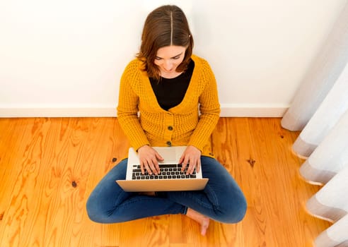 Beautiful woman sitting on the floor working with a tablet